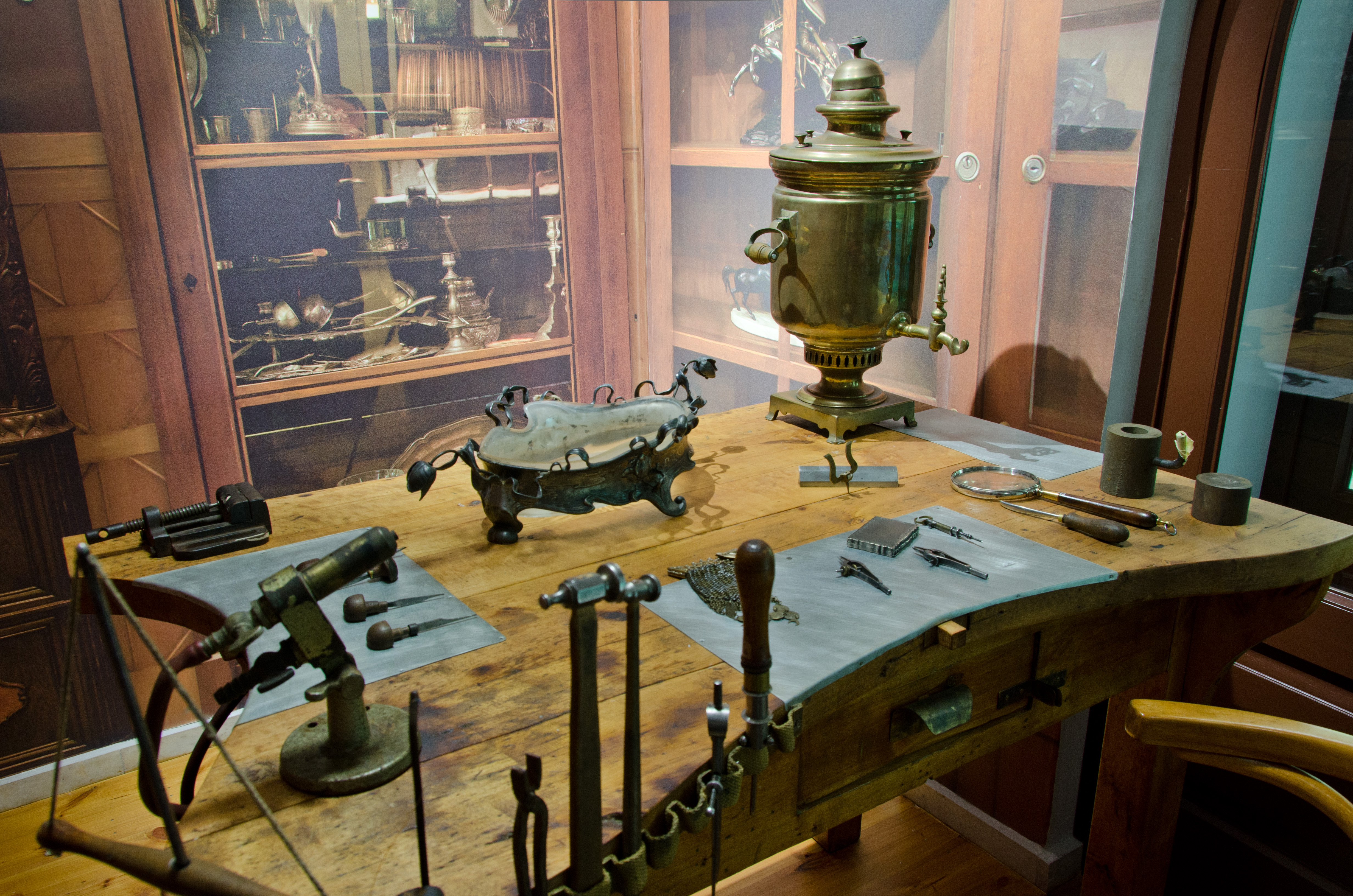 Widok na część wystawy historycznej o mieœcie - zakład ślusarski i grawerniczy z odtworzonym stołem roboczym, narzędziami do grawerowania i obróbki metali.