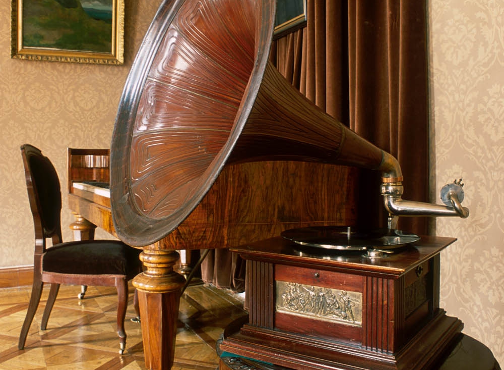 Zbliżenie gramofonu mechanicznego z tuba, z mechanizmem sprężynowym w skrzynce drewnianej.
