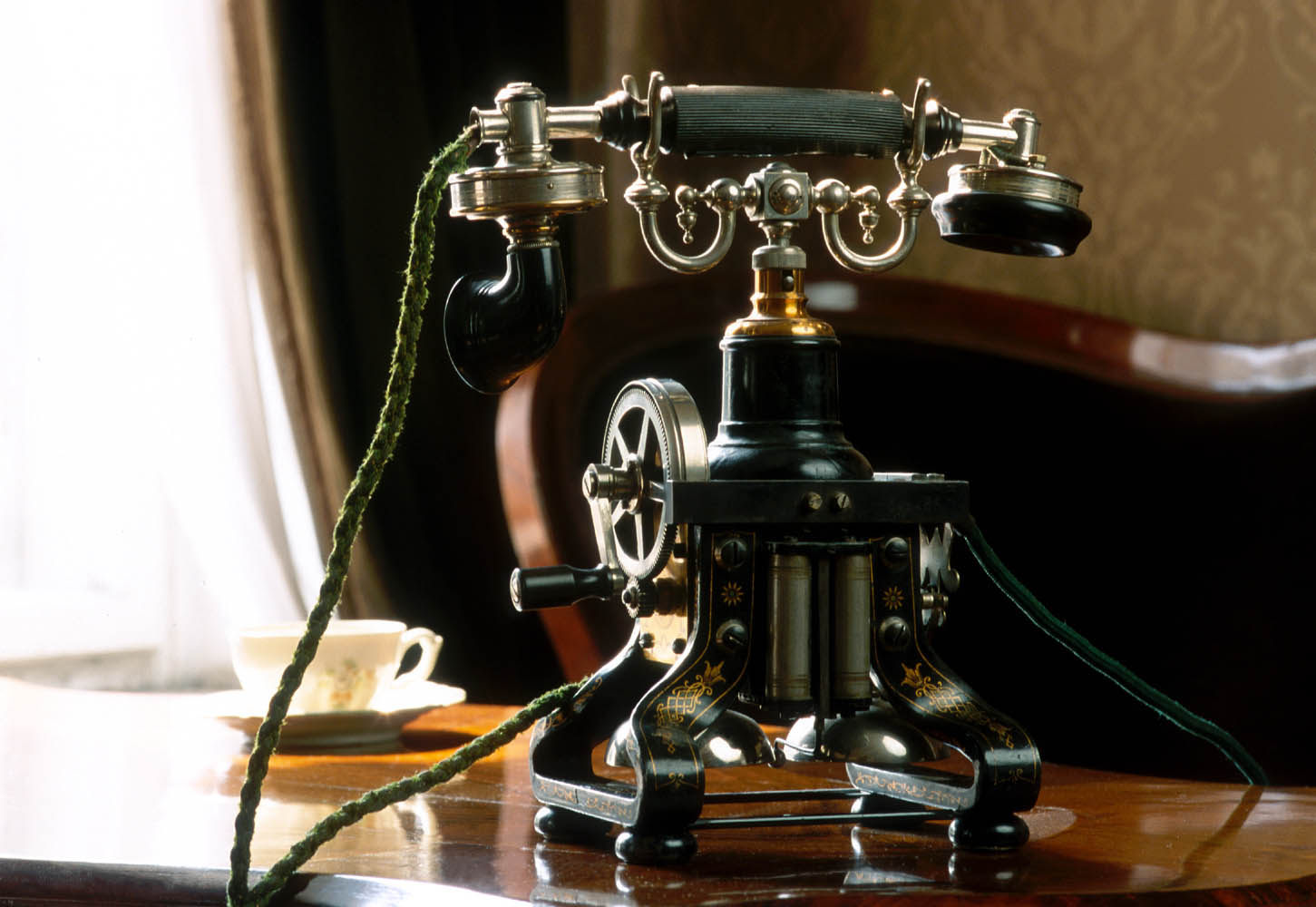 Widok aparatu telefonicznego z początku dwudziestego wieku, w którym połączenie wywoływało się poprzez pokręcenie korbki i rozmowę z telefonistą, który łączył z odpowiednim abonentem.