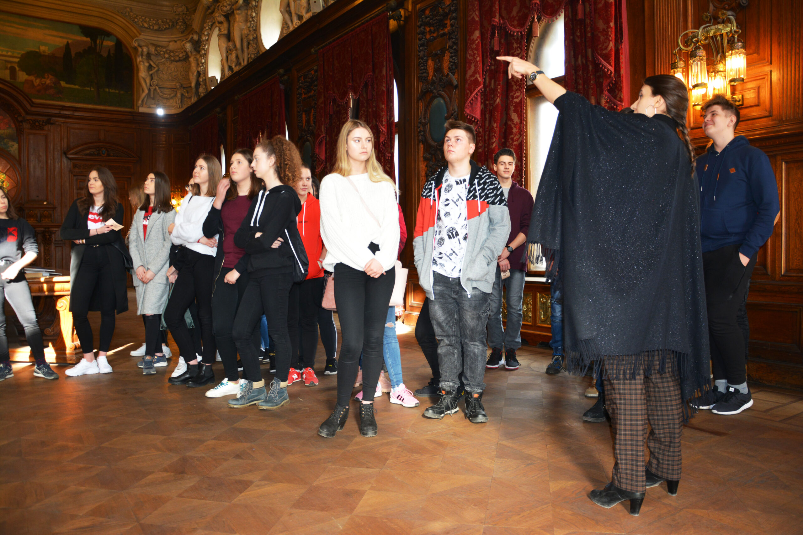 Przewodnik oprowadza grupę młodzieży.